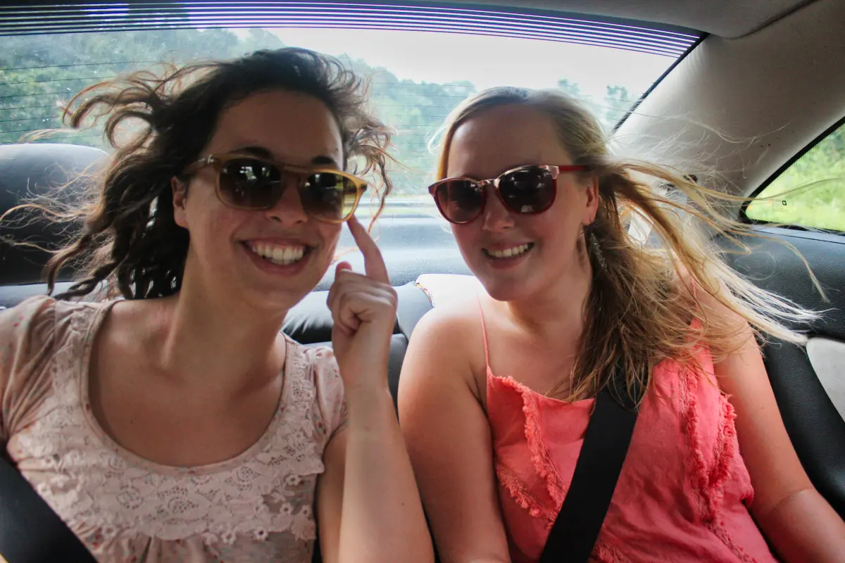 girls wearing sunglasses inside a car with wind in their hair