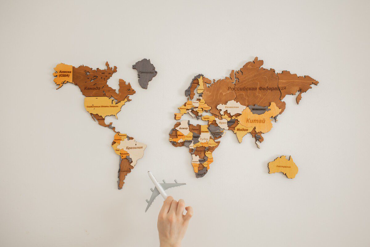 How to create a travel bucket list to see the world. World map with hand holding a plane