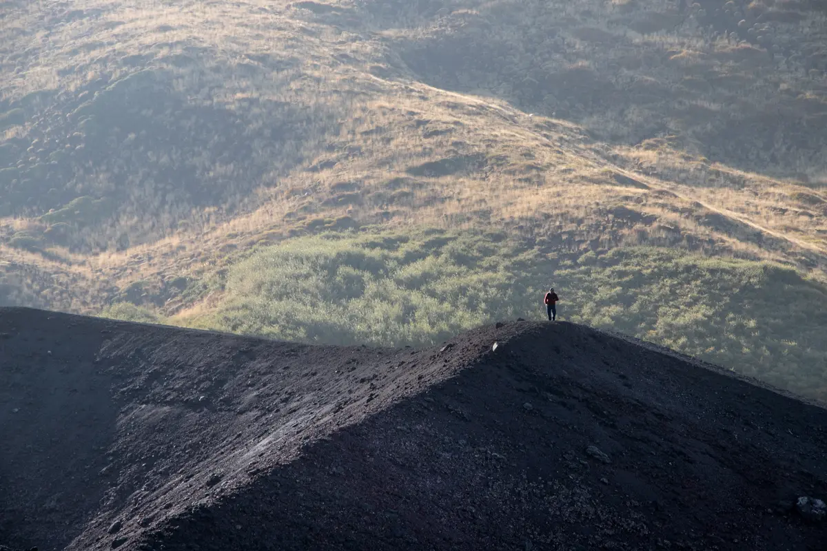 silhouette standing on lava black dune on mount etna