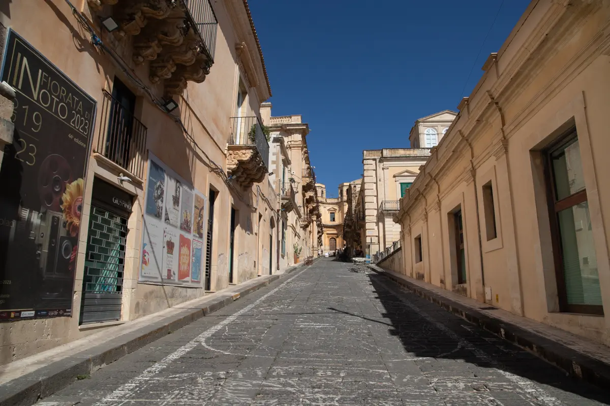 view of a downhill street with decorated ground via corrado nicolaci in noto